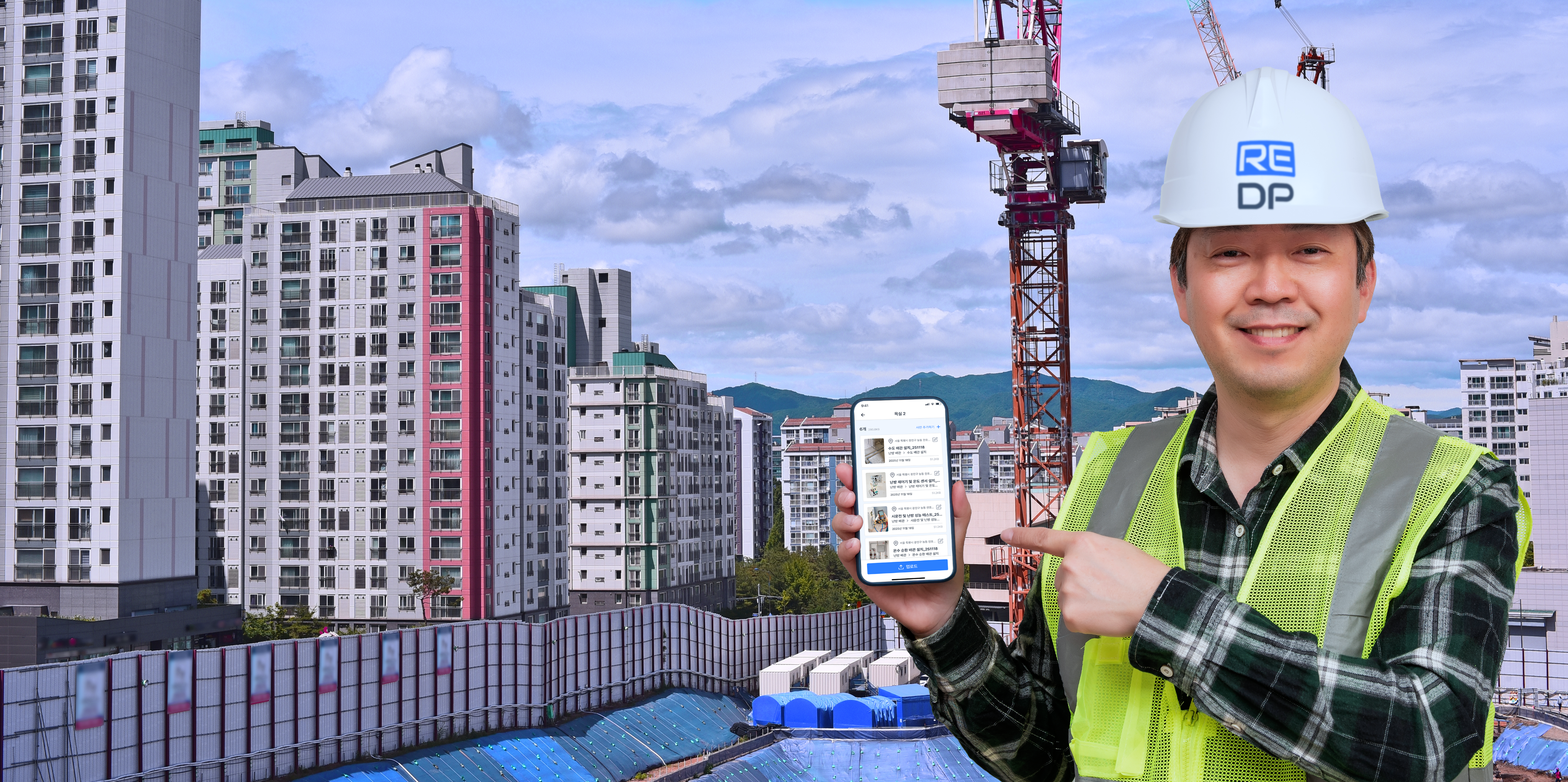 건설현장 작업자가 리네임 DP 화면이 열린 휴대폰을 가리키는 모습